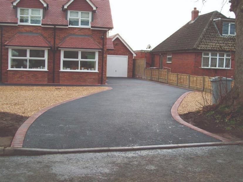 Sweeping tarmac driveway with red block edging